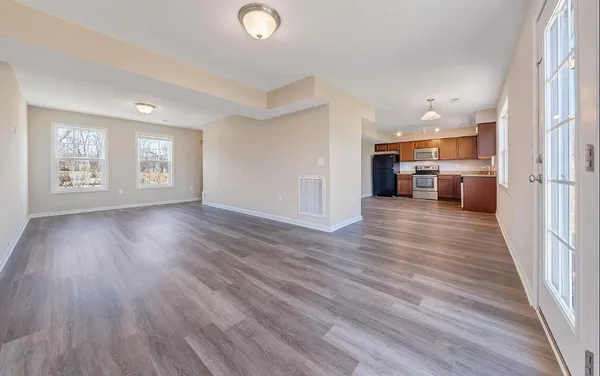 an empty room with wooden floor and windows