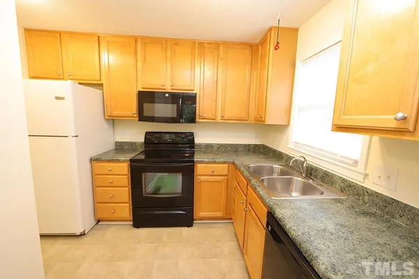 a kitchen with granite countertop a refrigerator a stove top oven and a sink