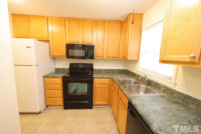 a kitchen with granite countertop a refrigerator a stove top oven and a sink