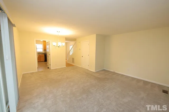a view of an empty room and a kitchen