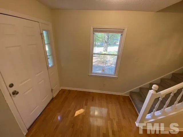 a view of an empty room with wooden floor and a window
