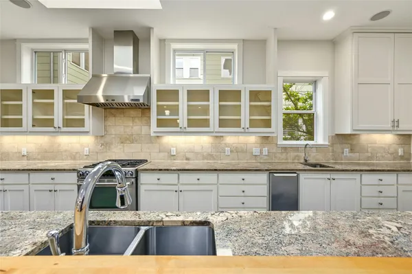 a kitchen with granite countertop stainless steel appliances sink stove and cabinets