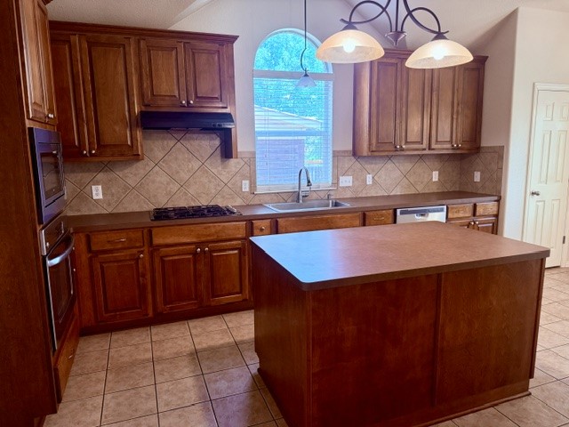 20724 Kearney Hill Road Pflugerville, TX 78660 - Photo 18 of 40 Kitchen featuring a central island, wood cabinetry, tile flooring, tile backsplash, and a built-in oven