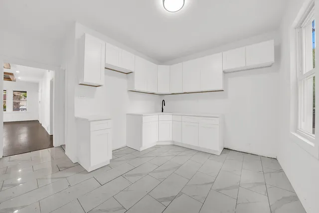 a view of a kitchen with white cabinets and entryway