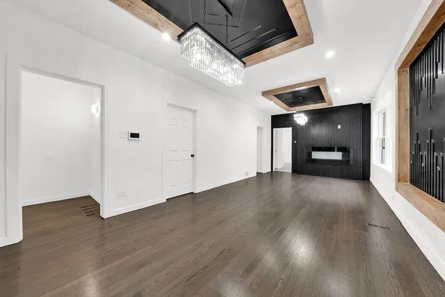 a view of an empty room with wooden floor and a kitchen