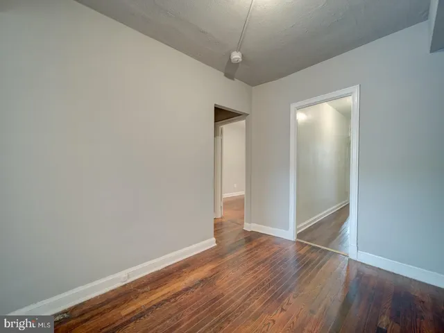 an empty room with wooden floor closet and windows