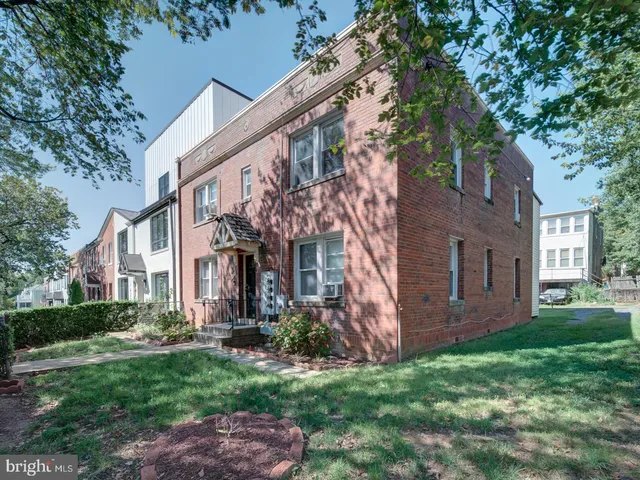 a view of a brick house with a large windows and a big yard and large trees