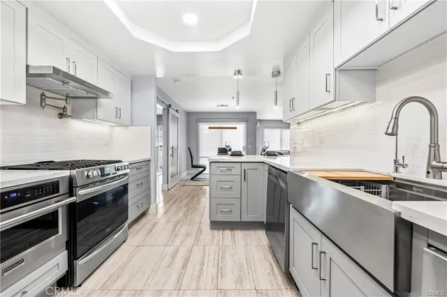 a kitchen with stainless steel appliances granite countertop a sink a stove and a refrigerator