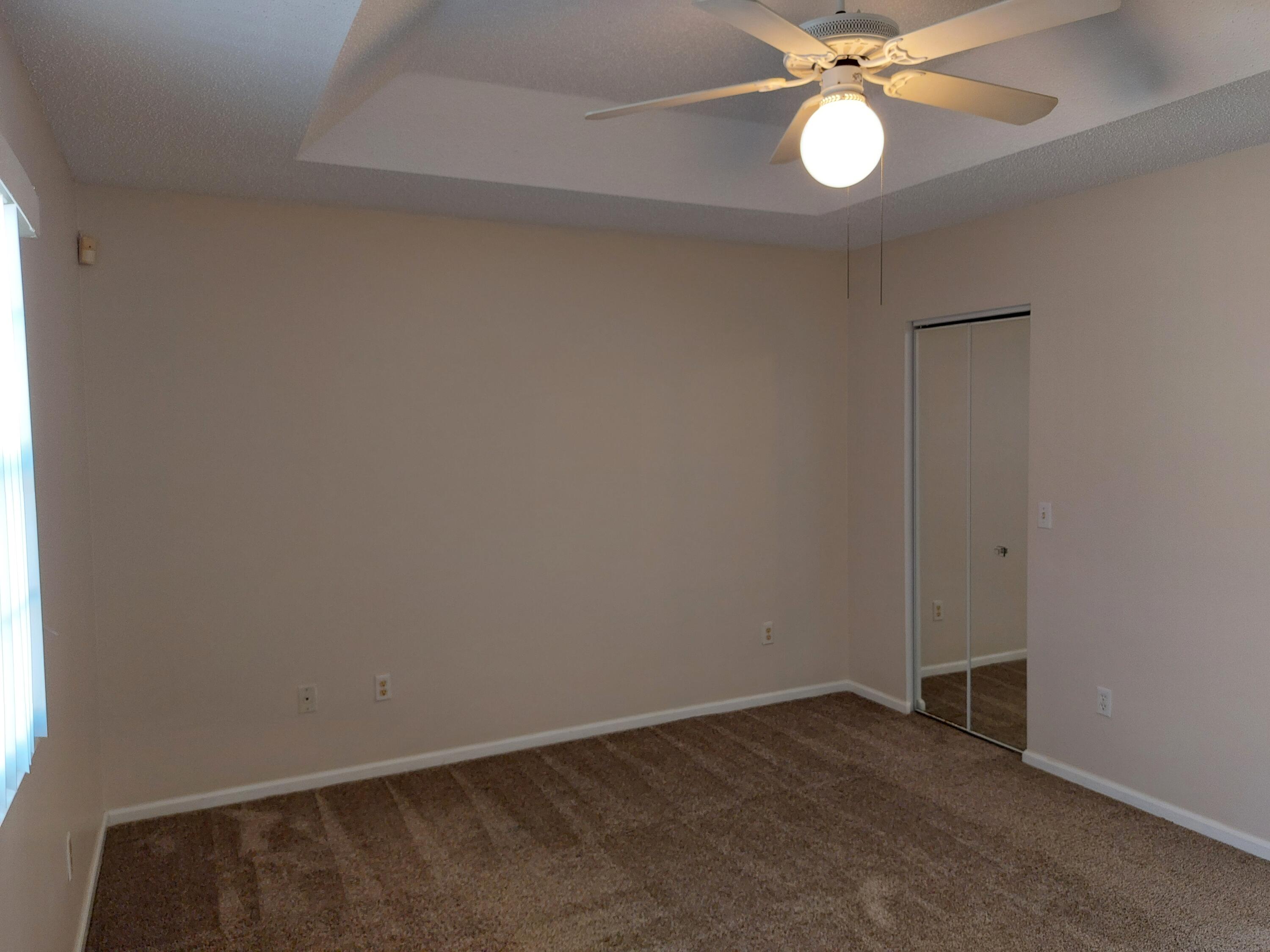331 Oak Crest Terrace, Unit 331 Jupiter, FL 33458 - Photo 18 of 29 an empty room with a chandelier fan and wooden floor