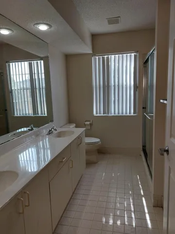 a bathroom with a granite countertop sink a toilet and with mirror