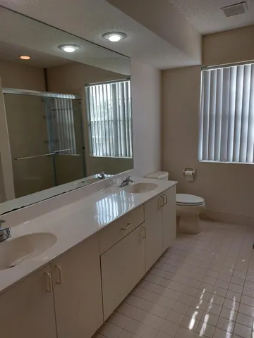 a bathroom with a granite countertop sink a toilet and a large mirror