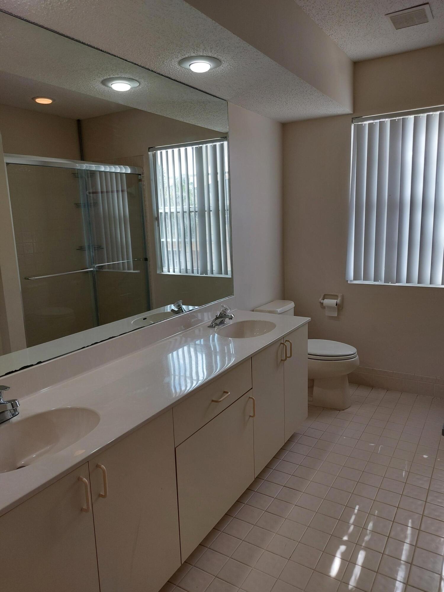 331 Oak Crest Terrace, Unit 331 Jupiter, FL 33458 - Photo 21 of 29 a bathroom with a granite countertop sink a toilet and a large mirror
