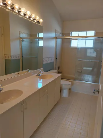 a bathroom with a sink a toilet a mirror and shower