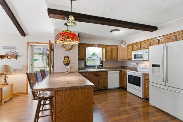 a kitchen with stainless steel appliances granite countertop a stove a sink dishwasher and a dining table with wooden floor