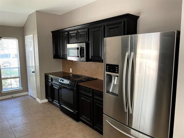 a metallic refrigerator freezer sitting in a kitchen