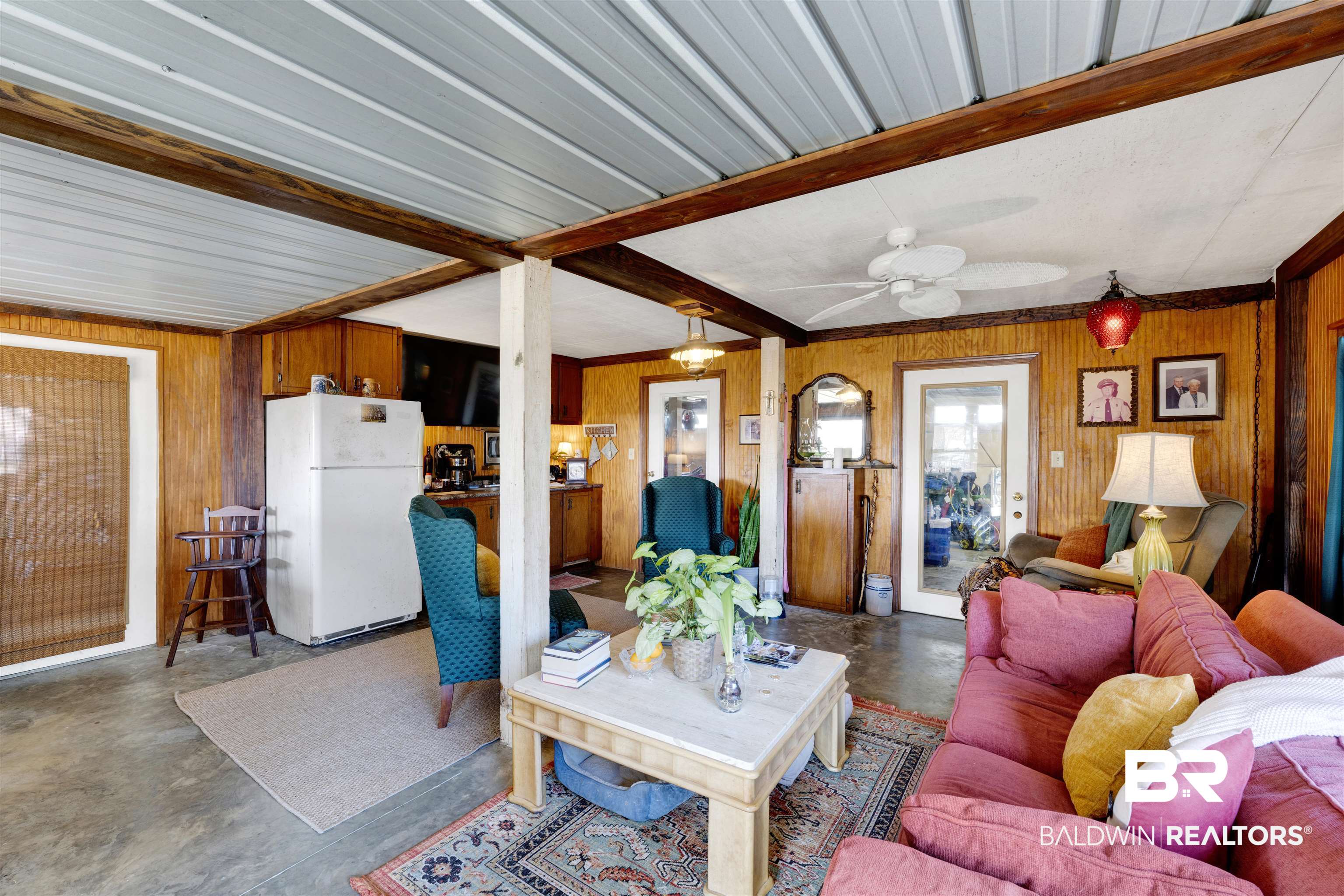 26222 Marina Road Orange Beach, AL 36561 - Photo 26 of 38 Living area featuring concrete flooring, beamed ceiling, a ceiling fan, and wooden walls