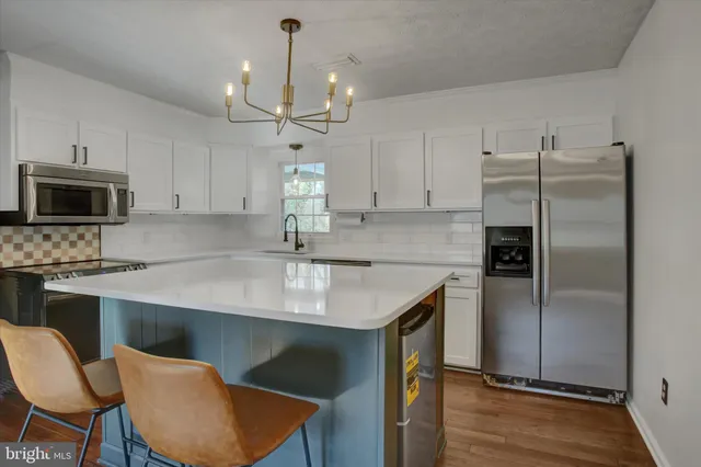a kitchen with kitchen island a counter space a sink appliances and cabinets