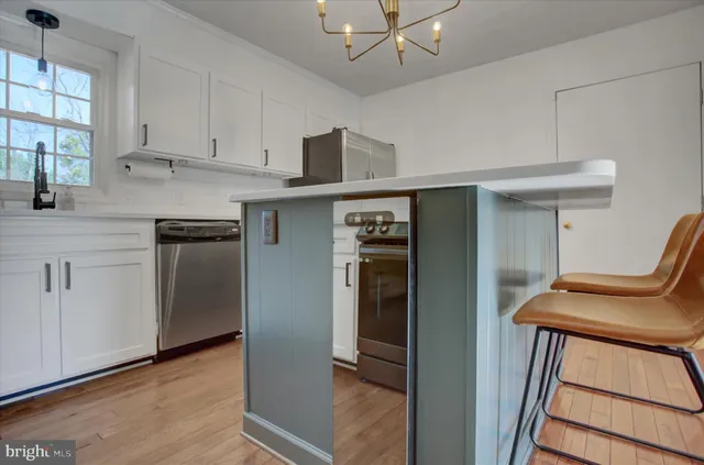 a kitchen with stainless steel appliances granite countertop a refrigerator a sink and white cabinets
