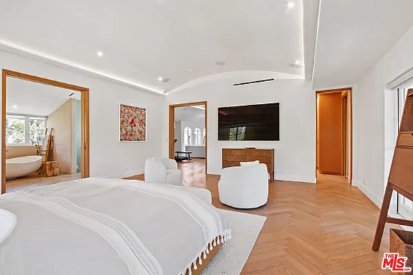 a living room with couches chairs and a dining table with wooden floor