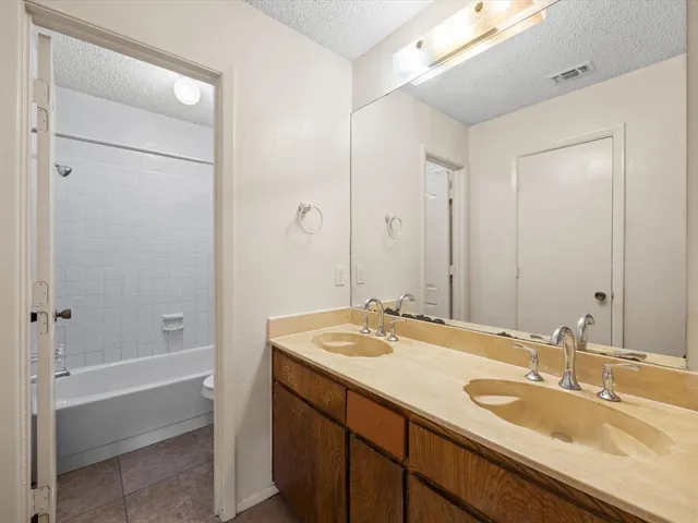 a bathroom with a sink double vanity granite tub shower and a mirror