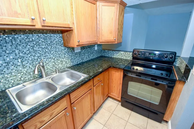 a kitchen with granite countertop a sink stove and cabinets