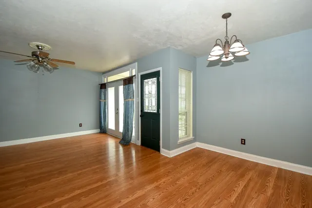 a view of a livingroom with a chandelier fan and windows