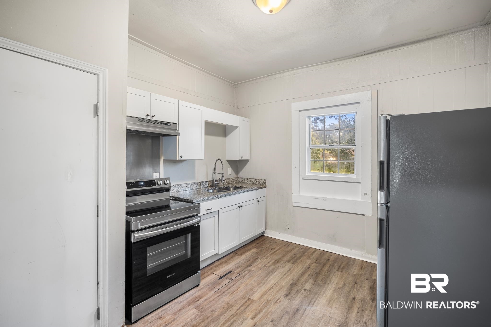 401 Gaston Street Mobile, AL 36603 - Photo 12 of 17 Kitchen featuring light hardwood / wood-style floors, sink, stainless steel appliances, light stone countertops, and white cabinets
