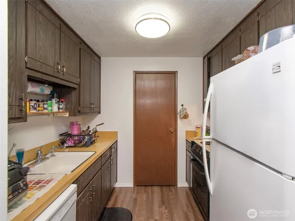 a kitchen with refrigerator a sink dishwasher and a stove with wooden floor