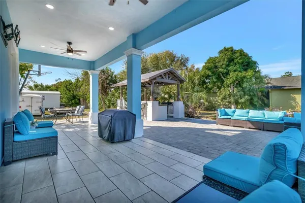 a view of a patio with table and chairs barbeque potted plants and large tree