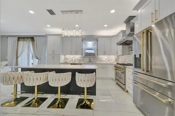 a kitchen with granite countertop a table chairs stove a refrigerator and cabinets