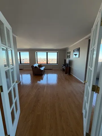 a view of an empty room with wooden floor and a window