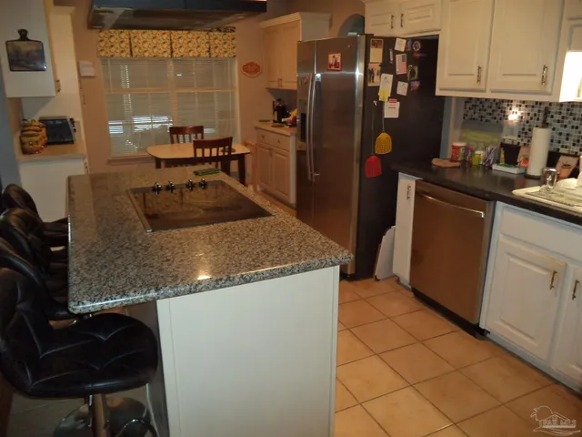a kitchen with granite countertop a refrigerator a stove and a sink