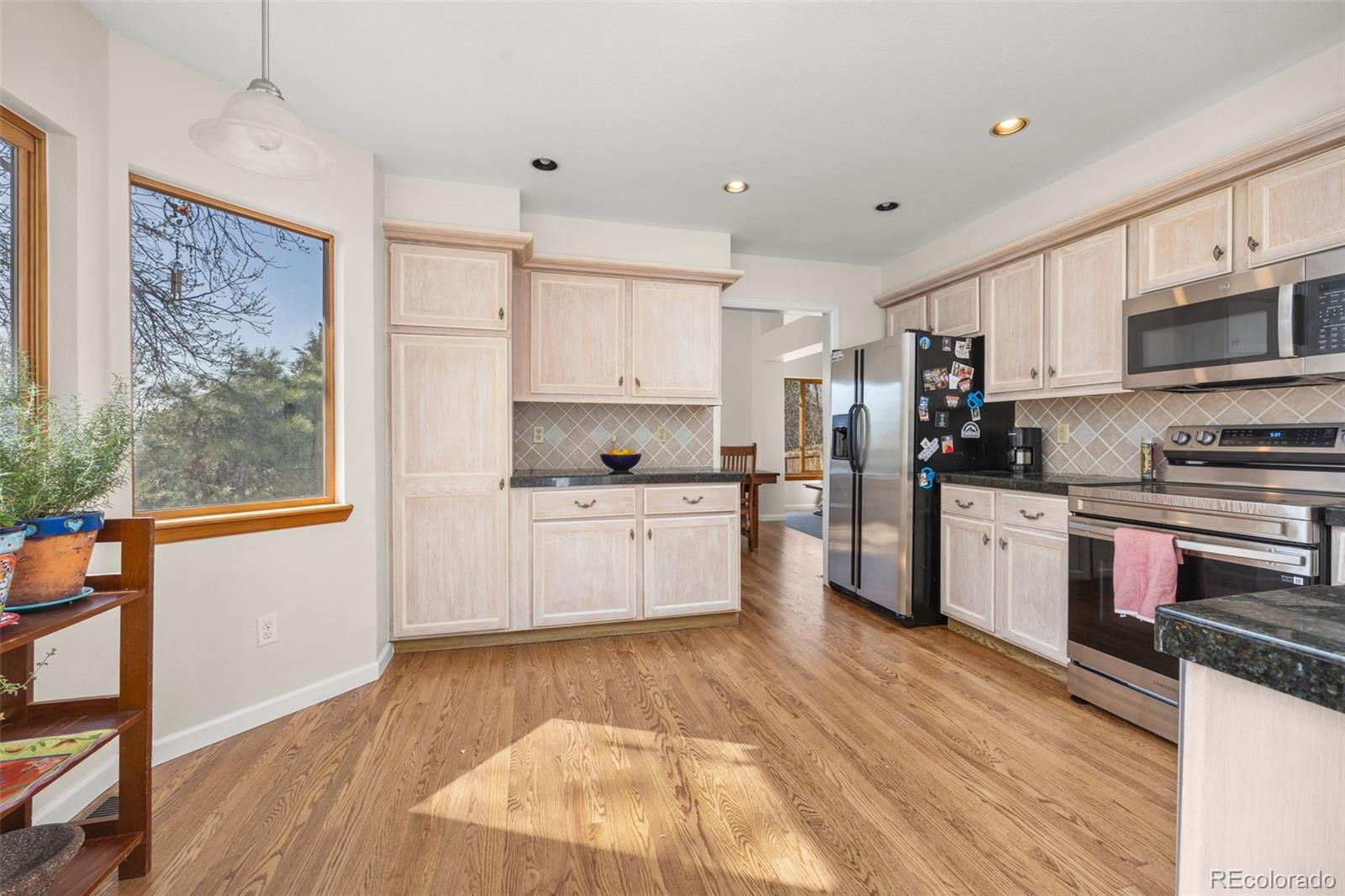 6868 Johnson Street Arvada, CO 80004 - Photo 9 of 39 a kitchen with stainless steel appliances wooden floors and white cabinets