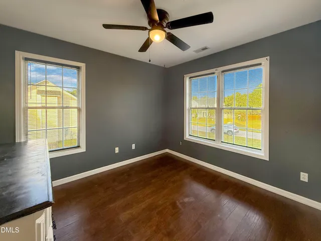 a view of an empty room with a window and wooden floor