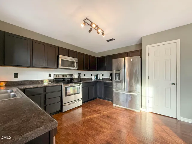 a kitchen with granite countertop a refrigerator stove top oven and sink