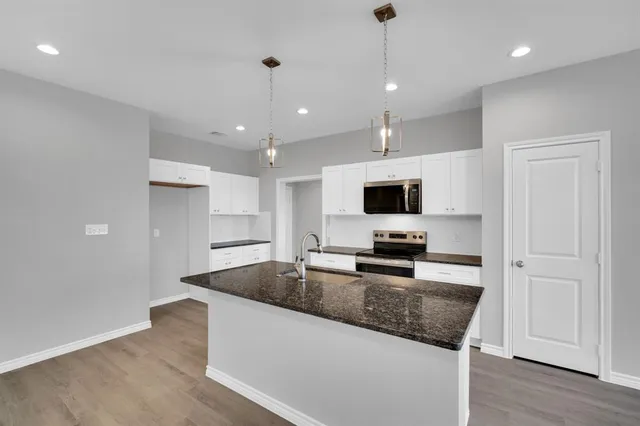 a large kitchen with granite countertop a large counter top stainless steel appliances and cabinets