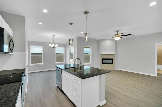 a kitchen with granite countertop a sink a counter top space and stainless steel appliances