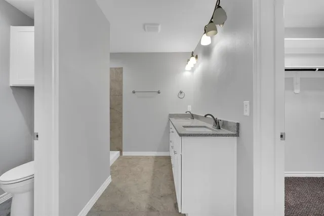 a bathroom with a granite countertop sink and a toilet