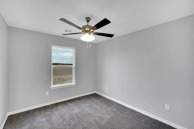 an empty room with a window and a fan