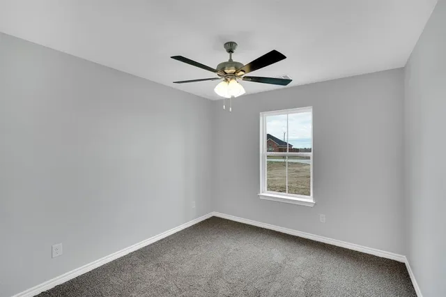 an empty room with a window and a fan