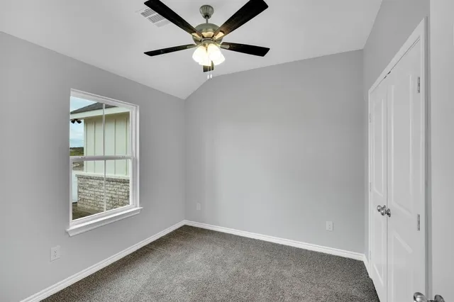 an empty room with windows and fan
