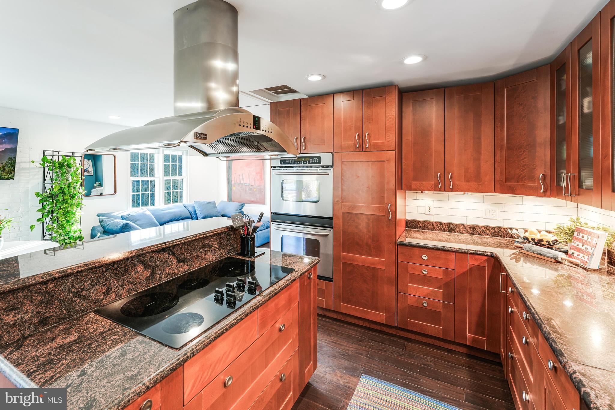 10808 Beach Mill Road Great Falls, VA 22066 - Photo 13 of 43 a kitchen with stainless steel appliances kitchen island granite countertop a stove a refrigerator a sink and dishwasher with wooden floor