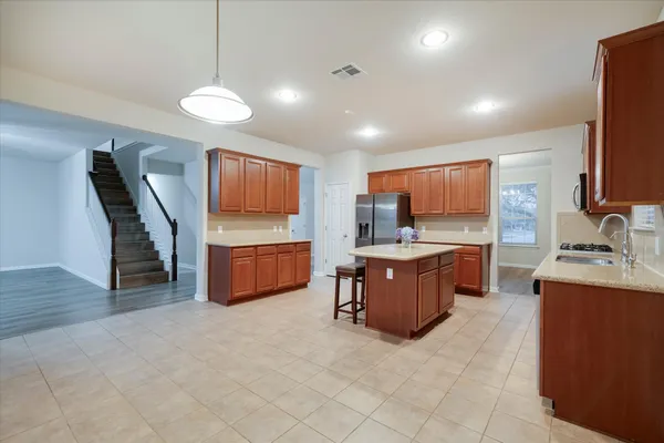 a kitchen with stainless steel appliances kitchen island granite countertop a refrigerator a sink a stove and island