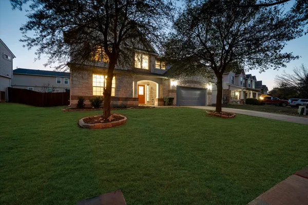 a front view of a house with garden and trees