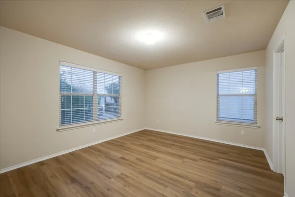 a view of an empty room with window and wooden floor