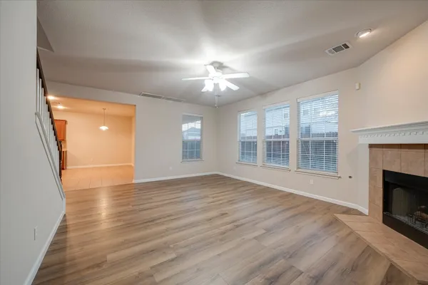 a view of an empty room with wooden floor fireplace and a window