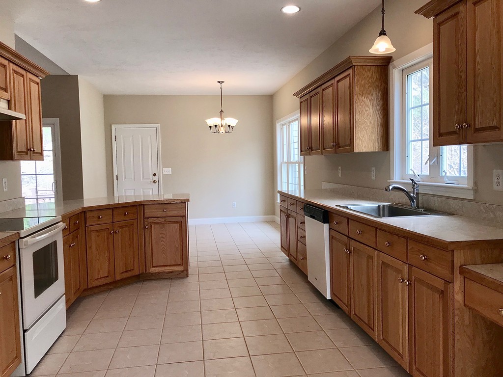 408 Nicholas Drive Lancaster, MA 01523 - Photo 9 of 30 a large kitchen with kitchen island granite countertop a sink counter top space and cabinets