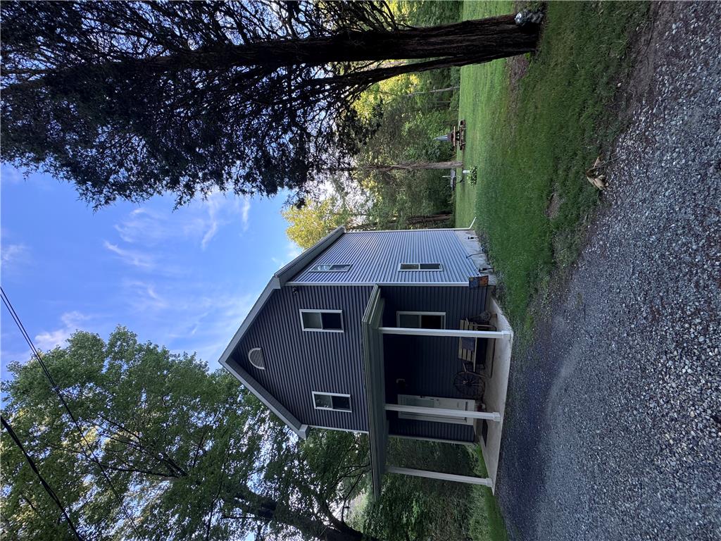 130 Hidden Spur Road Lehighton, PA 18235 - Photo 3 of 19 A charming residence with a covered front porch, set against a backdrop of mature trees and a gravel driveway.