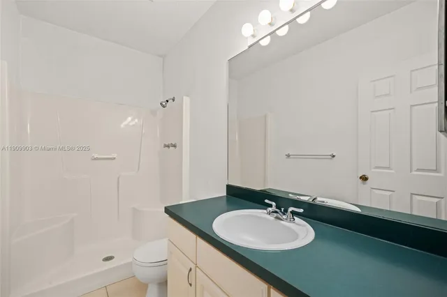 a bathroom with a sink a toilet a mirror and shower