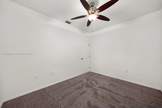 an empty room with a fan & a window